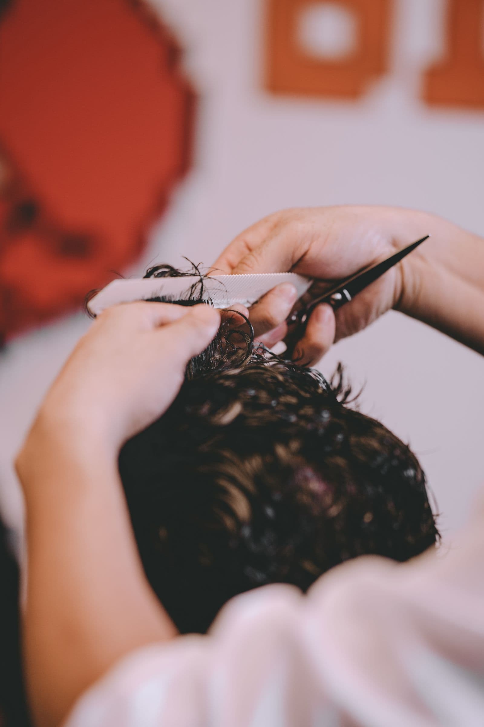 A hairstylist combing and cutting a client’s wet hair in a salon